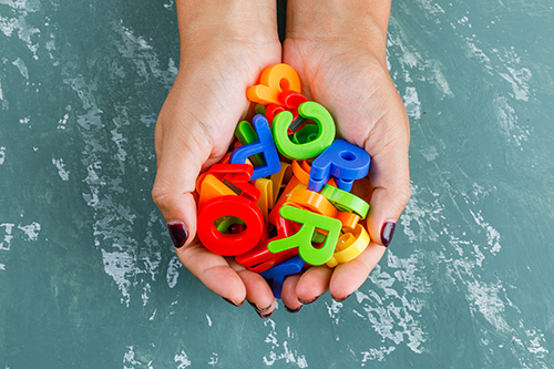 Back to school concept on plaster background flat lay. woman holding colorful letters.
