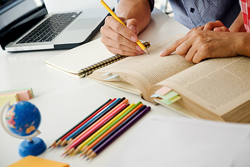 Education concept. Students studying and brainstorming campus concept. Close up of students discussing their subject on books textbooks and writing to notebook. Seclective focus.